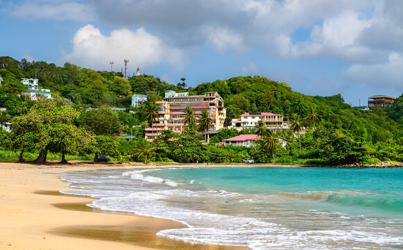 Scenic view of the sandy shore, turquoise ocean water, and hillside buildings at Vigie Beach in Castries, Saint Lucia.