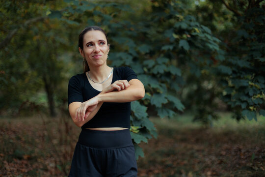 Stressed Woman Scratching Her Itchy Arm in a Forest. Anxious female explorer scratches her itchy arm after insect bite in lush forest