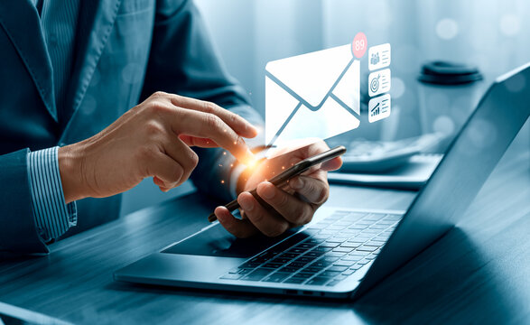 Email marketing communication concept with business professional using smartphone beside laptop showing virtual message notification, customer audience, campaign target and performance analytics