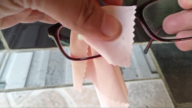 Close-up hand cleaning eyeglasses with a microfiber cloth