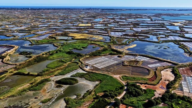 Panoramic aerial view of vast Guerande salt marshes with colorful salt pans, lagoons, dikes and wetlands stretching to Atlantic Ocean horizon near Plage des Oceanides, France