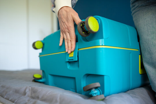 Luggage packing and travel security, woman hand pressing down on plastic suitcase clip lock, female finished packing personal travel case and closing baggage with latch clip on bottom of case.