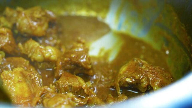 Tender chicken simmered in golden curry sauce, Close-up of tender chicken pieces simmered in a rich golden-brown curry sauce, showing glossy texture and warm homemade comfort food appeal.
