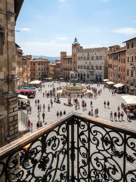 Historic Italian Piazza with Fountain and Crowds Under Blue Sky.