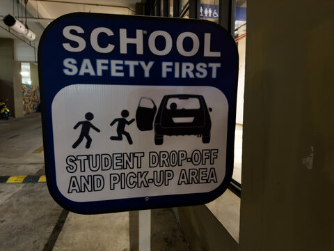 "School Safety First" sign marking a designated "Student Drop-Off and Pick-Up Area" with graphic icons. Ideal for educational, child safety, traffic management, and campus security stock footage.
