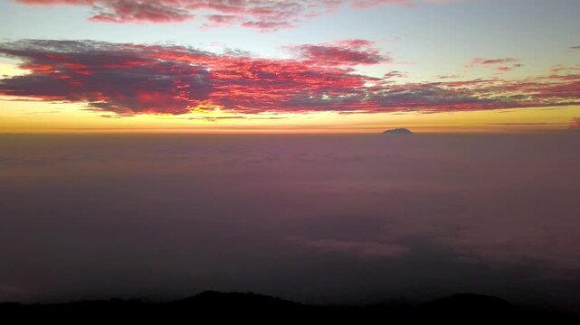 Aerial drone Sunset footage of Mount Merapi active volcano towering over Selo village and clouds in Central Java, Indonesia.