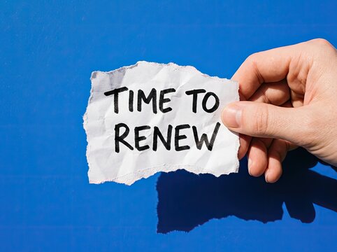 Hand holding paper with Time To Renew text suitable for business and finance marketing symbolizing fresh starts updates and goal resetting