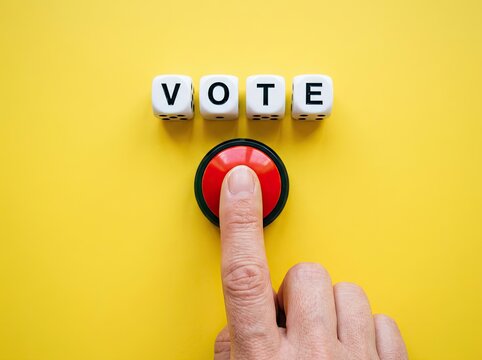 Finger pressing red button under VOTE blocks on yellow background ideal for election campaigns symbolizing civic choice and active participation