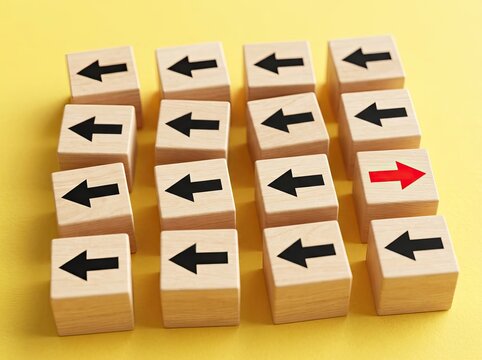 Wooden cubes with arrows pointing left except one red arrow pointing right ideal for leadership media symbolizing unique direction and choice