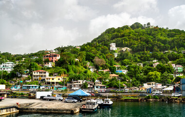 Obraz premium Waterfront pier with boats and colorful houses on a lush tropical hillside in Castries Harbour, Saint Lucia.