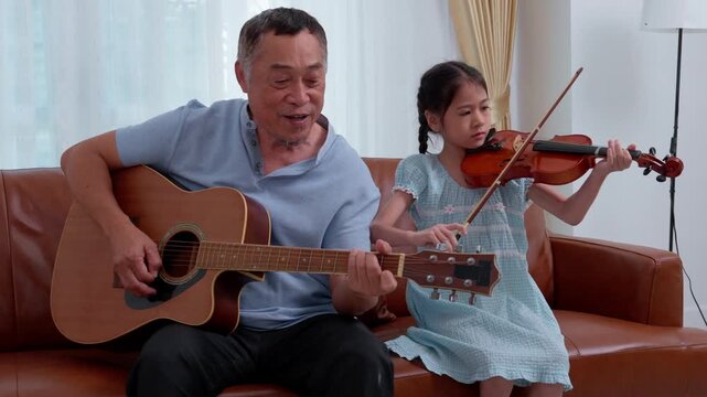 Asian family enjoys leisure time together at home, where a parent and child share a hobby playing violin. This moment reflects a lifestyle of love, childhood joy, and strong generational relationships
