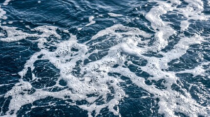 Obraz premium White sea foam and bubbles on dark blue ocean water surface