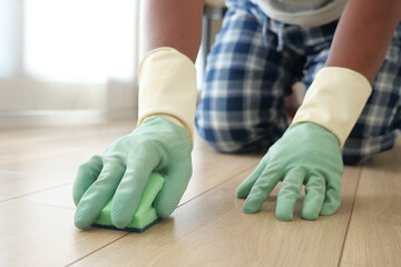 Obraz premium Man cleaning a floor using a sponge while wearing gloves