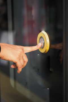 person's finger pressing a round, illuminated button or a biometric scanner mounted on a dark surface