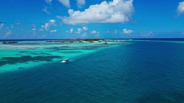 Drone shot of speedboat leaving white water wake in deep sea near paradise resort island. Dynamic visual asset for summer holiday, marine travel, and water sports promo.Maldives