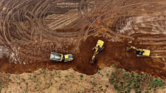 Top down aerial view shows heavy machinery including excavators and dump truck digging into brown earth at Hambach open pit mine