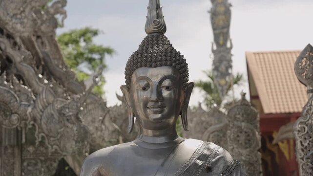 Close up of a silver Buddha statue face in backlight