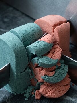 Close-up of a sharp metal knife slicing through vibrant blue and pink kinetic sand, creating satisfying textures and crumbling layers, high-quality macro photography for sensory and stress relief cont