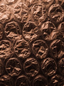 Macro Abstract Background of Brown Bubble Wrap Plastic Packaging Material, Detailed Texture of Air Filled Protective Film, Close-up Industrial Pattern for Shipping, Logistics and E-commerce Design