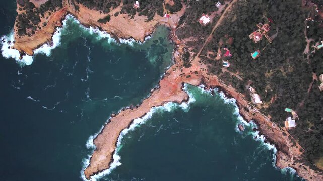 4K top-down drone view of Sa Punta Galera in Ibiza, Spain. Distinctive flat rock formations contrast with the crystal-clear Mediterranean waters along this spectacular rocky coastline.