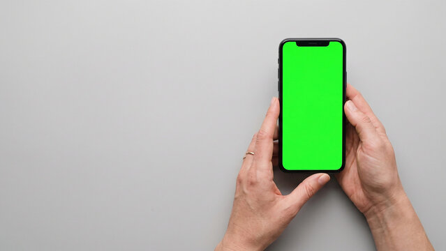 hand holding smartphone with green screen, minimalistic editorial aesthetic on white background
