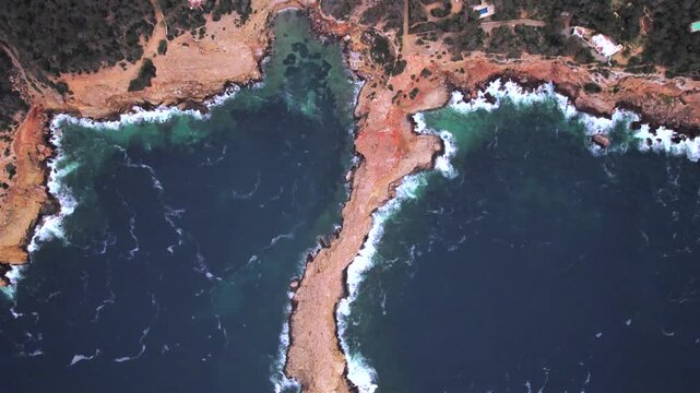 4K top-down drone view of Sa Punta Galera in Ibiza, Spain. Distinctive flat rock formations contrast with the crystal-clear Mediterranean waters along this spectacular rocky coastline.