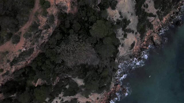 4K top-down drone view of Cap Blanc in Ibiza, Spain. Rocky formations, crystal-clear Mediterranean waters and rugged coastline create striking patterns along the coast near Es Vedr&agrave;.