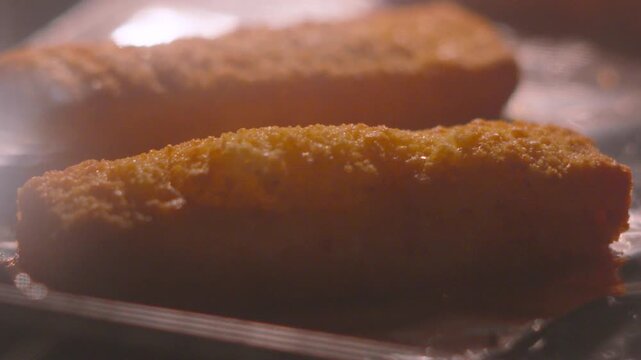Close-up View of Fish Fingers with Breadcrumb Coating Bubbling as Heat Escapes in Hot Oven.