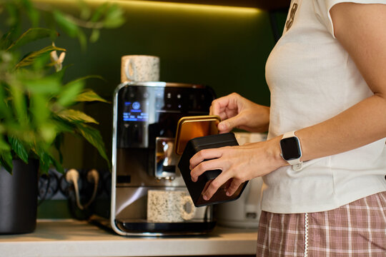 Woman preparing coffee at home near automatic coffee machine in coffee corner