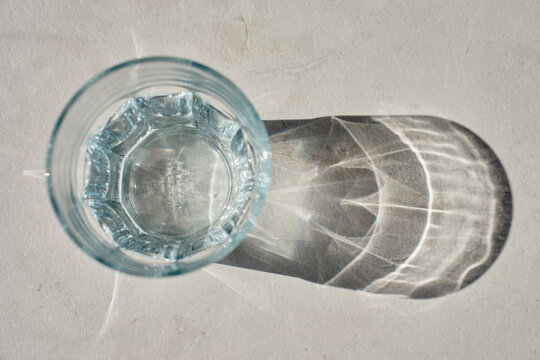 Glass of water in sunlight with shadow on countertop