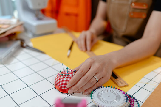 Professional fashion designer selecting fabric colors and sewing accessories in a modern studio. Creative textile design, garment production, tailoring craftsmanship and apparel development.