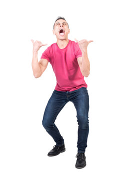 Full body of crazy male model wearing casual outfit yelling loud with opened mouth and showing rock n roll gesture against transparent background