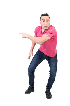 Full body of amazed male in casual clothes pointing aside and looking at camera with astonished face