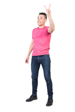 Full body of positive male model in casual outfit showing peace gesture and looking at camera