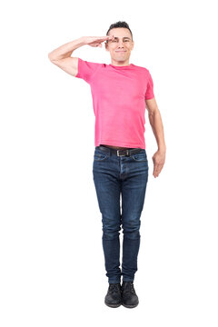 Full body of cheerful male soldier looking at camera and making salute gesture in studio