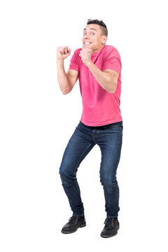 Full body of content male model with clenched fists looking at camera in modern light studio