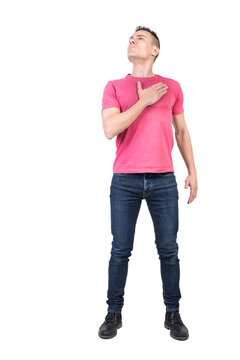 Full body of honorable male patriot looking up with hand on chest in light studio