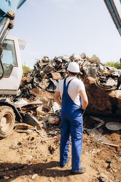Worker overseeing metal recycling operations at scrap yard