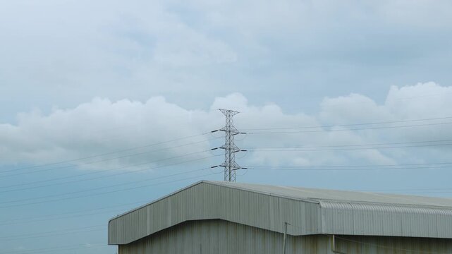 Time lapsed footage capturing the dynamic movement of clouds and warehouses in front pf Electrical Tower over cityscape timelapse. Climate change. Global warming. 