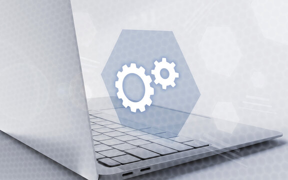 Una moderna computadora port&aacute;til con un icono de engranajes flotando sobre el teclado simboliza el desarrollo de software y la optimizaci&oacute;n de sistemas digitales.