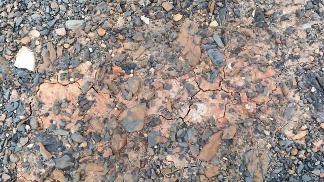 Cracked Dry Red Clay Soil with Gravel and Stones Ground Texture