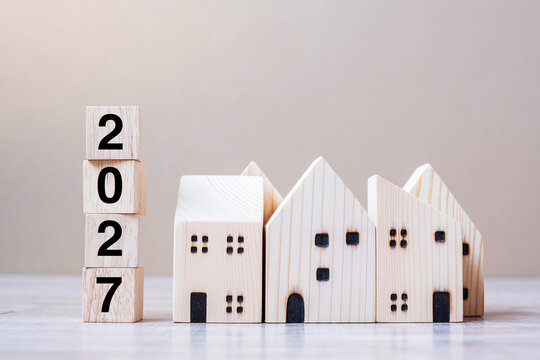 2027 Happy New Year with house model on table wooden background. Banking, real estate, investment, financial, savings and New Year Resolution concepts