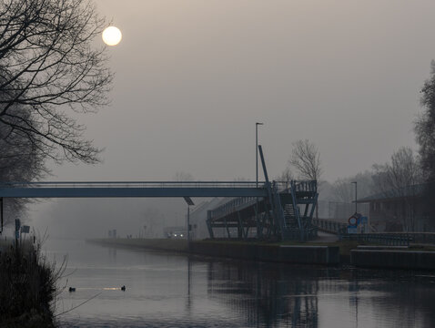 Misty Winter Morning over a Canal with Pedestrian Bridge at Foggy Sunrise