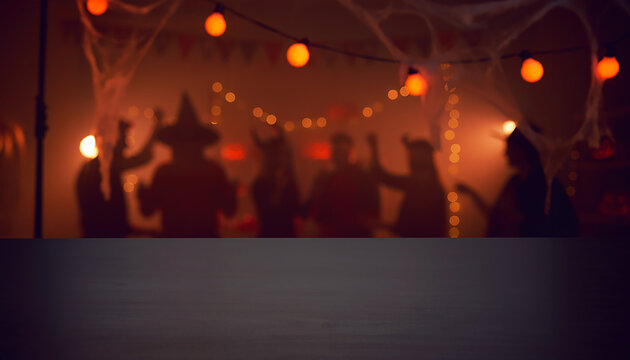 Empty Wooden Table Top in Foreground with Blurred Halloween Party Silhouettes Dancing in Background for Seasonal Product Display Concept