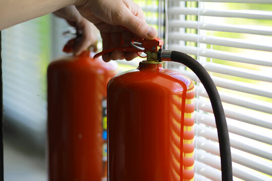 hand presses the trigger fire extinguisher available in fire emergencies conflagration damage background. Safety
