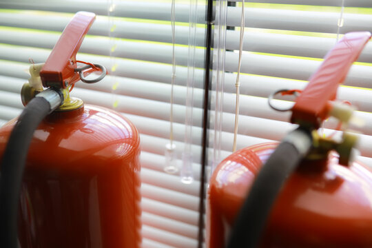 hand presses the trigger fire extinguisher available in fire emergencies conflagration damage background. Safety