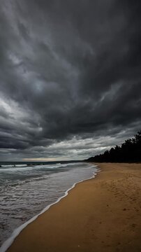Dramatic View of Dark Storm Clouds Above Calm Sandy Beach with Waves Crashing on Shore