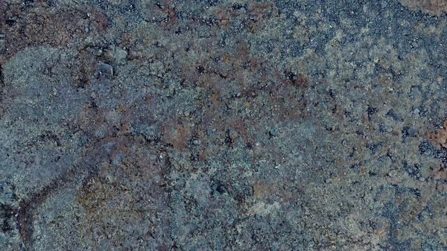 High altitude top down drone shot detailing surface texture of lichen covered granite bedrock on subarctic tundra