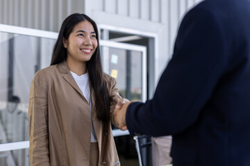 Cheerful Asian businesswoman smiling while shaking hand with partner during an office meeting celebrating successful corporate deal © eakgrungenerd
