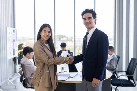 Happy professional business man and woman with confident smile share handshake in office meeting for partnership agreement success